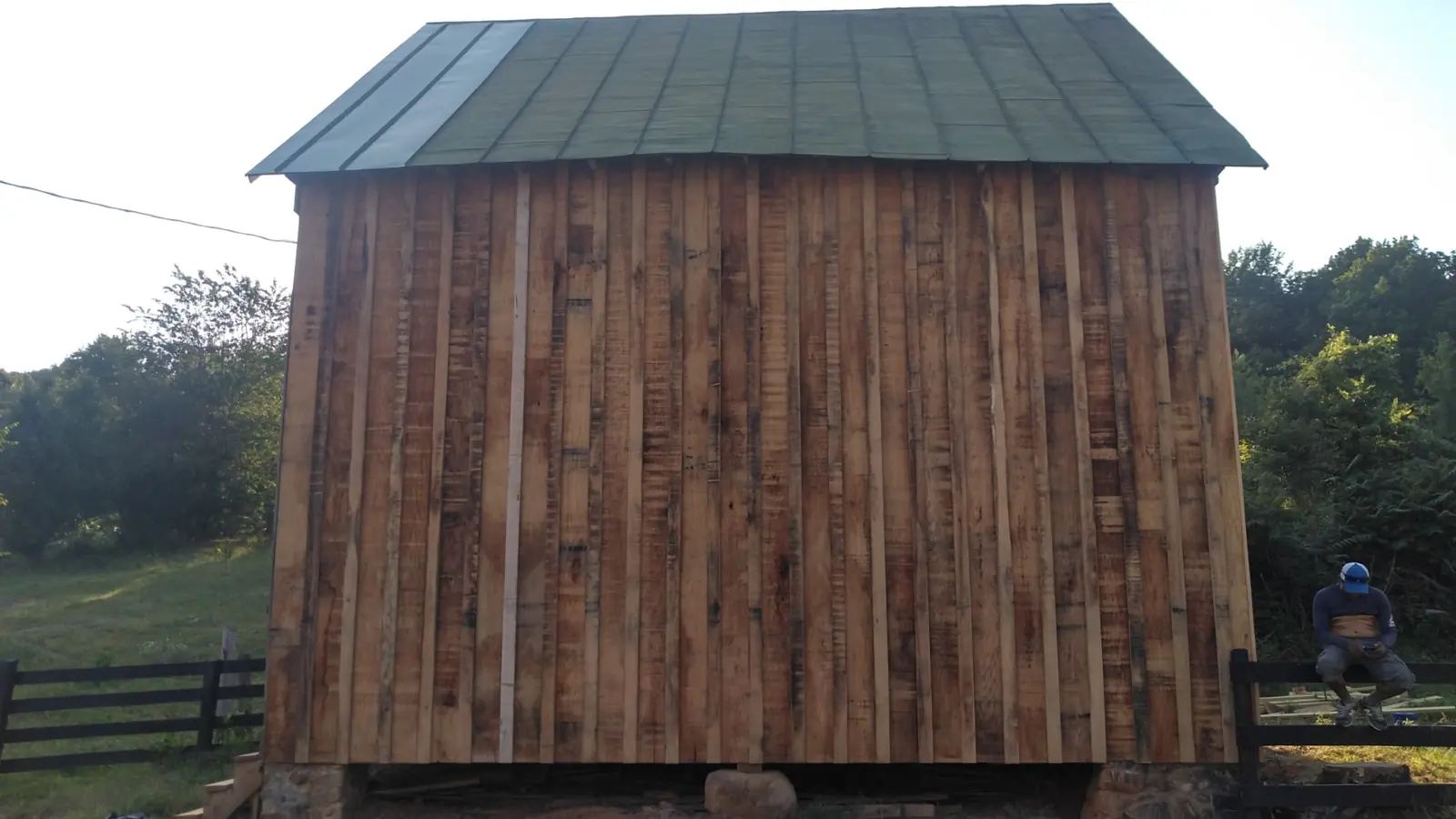 Barn with vertical wood siding under a finished green standing seam metal roof.