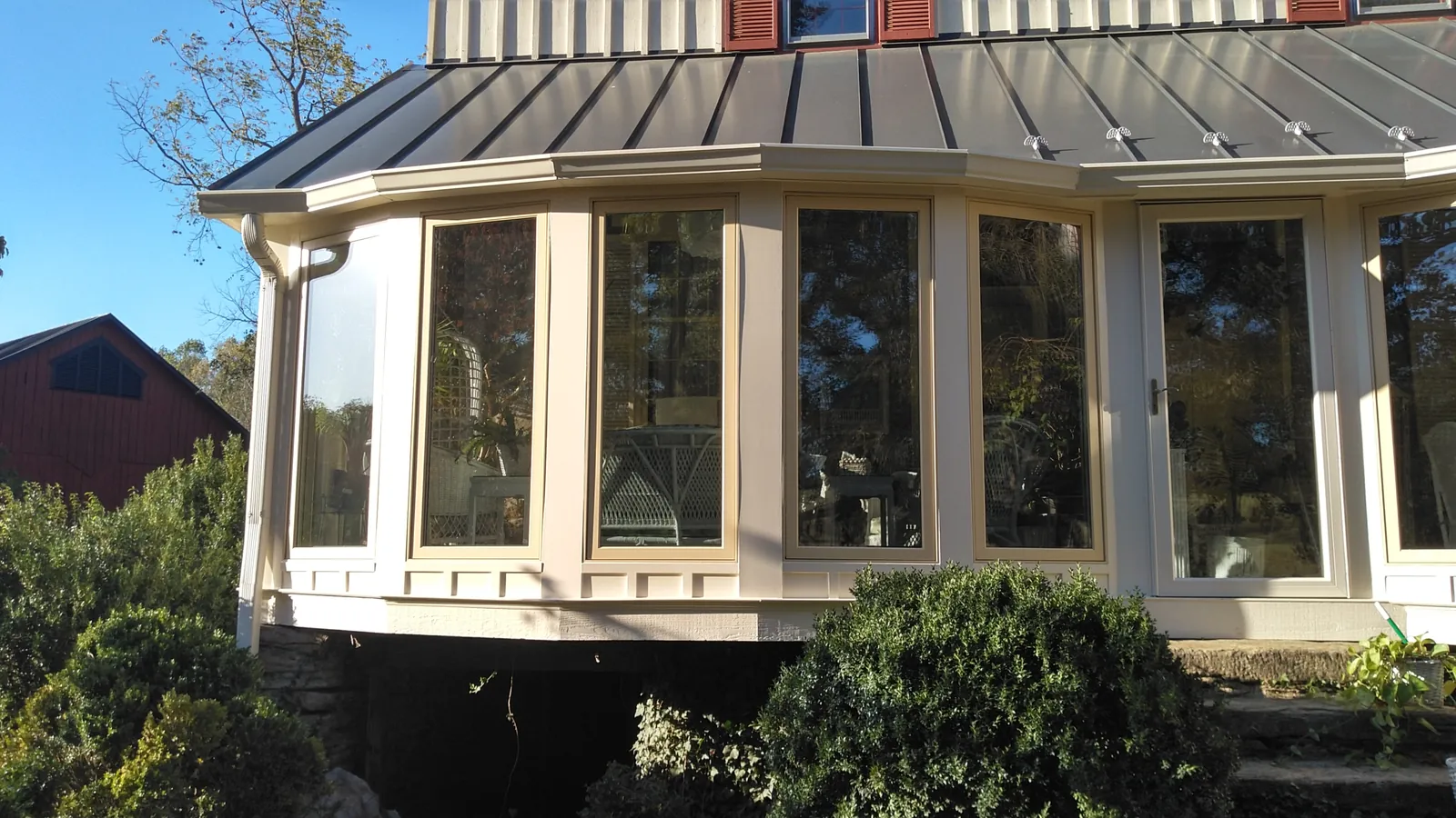 Wide cream-colored bay window beneath a dark standing seam roof edge.