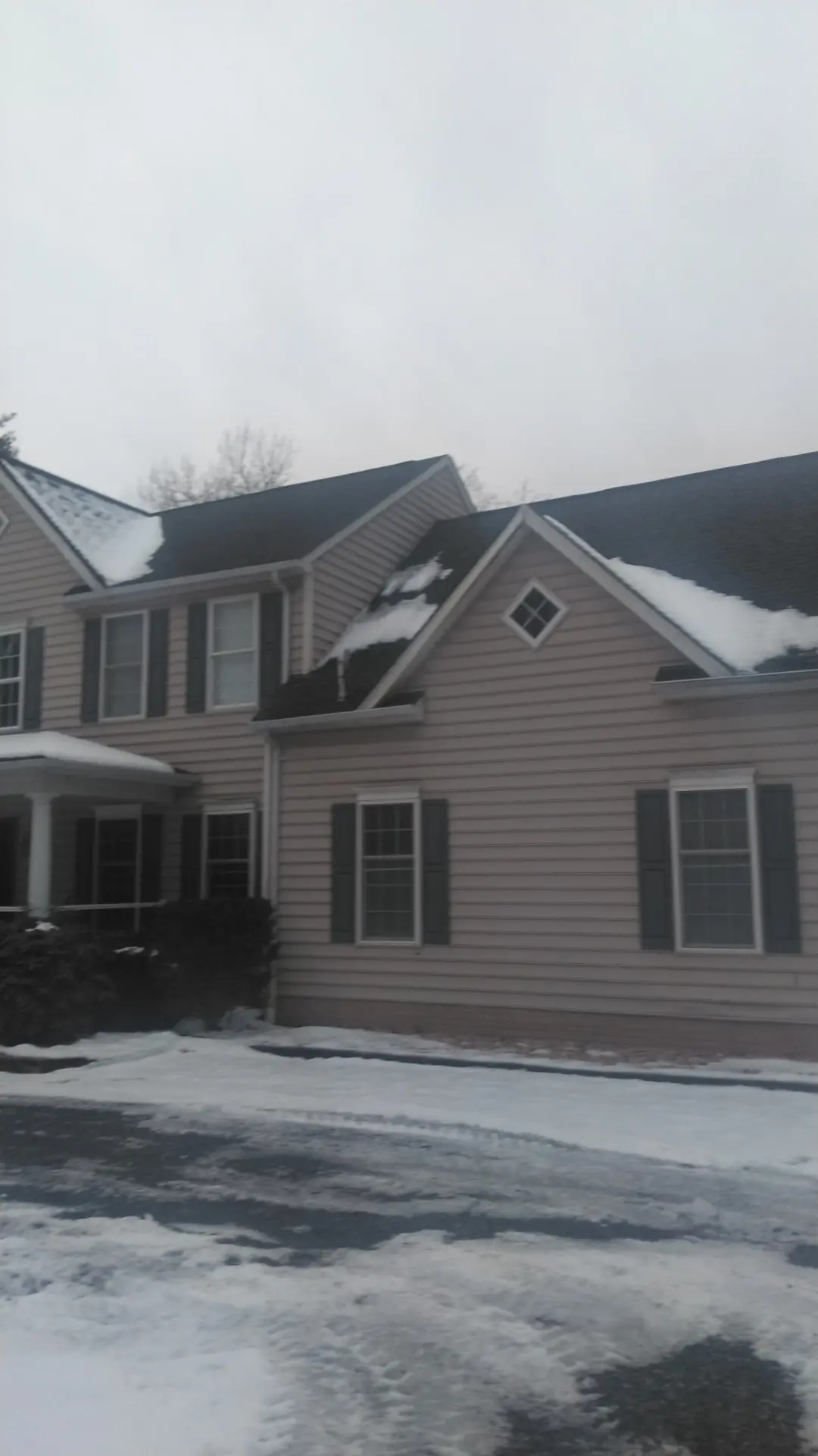 Side and front gable of a beige two-story home with dark shingles.