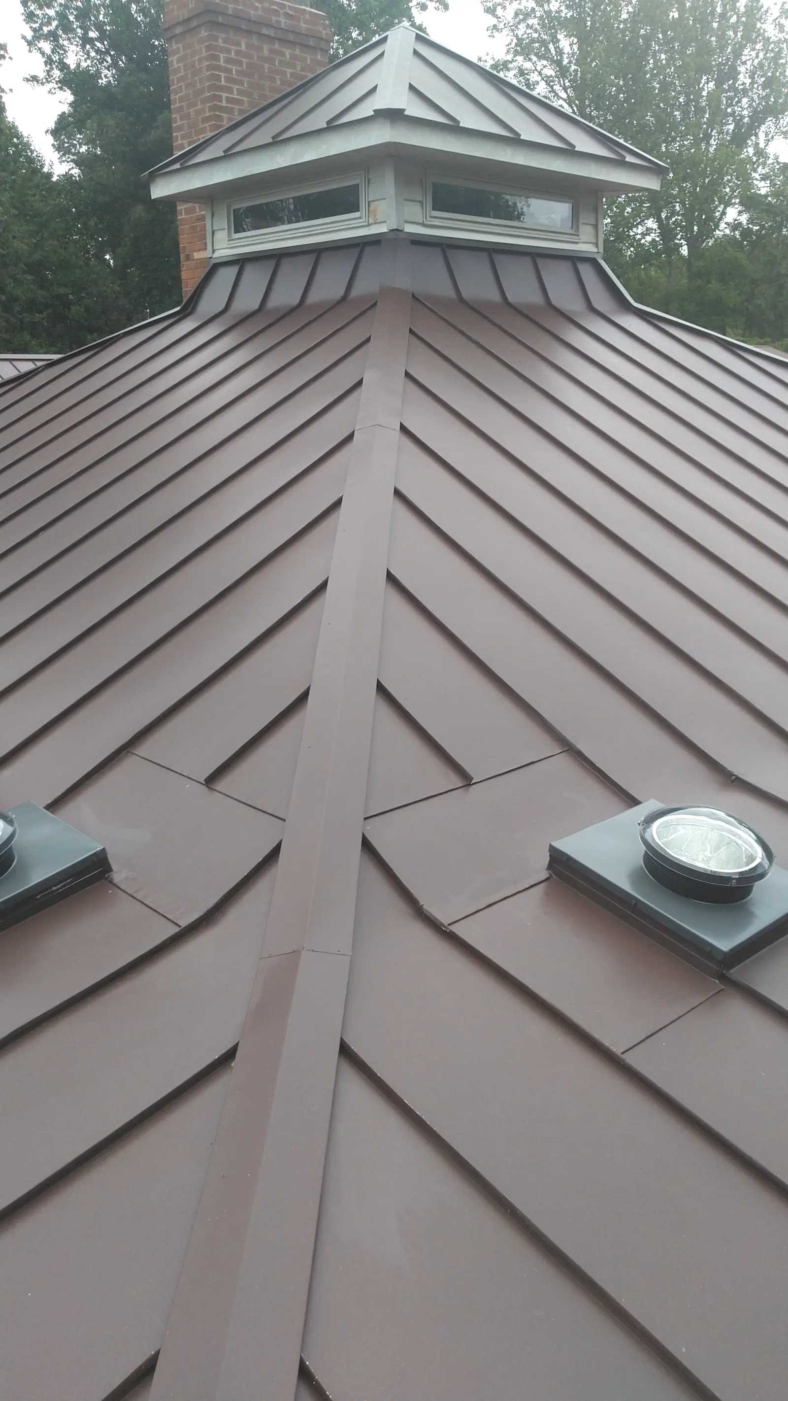 Cupola on a bronze standing seam hip with a skylight dome below.
