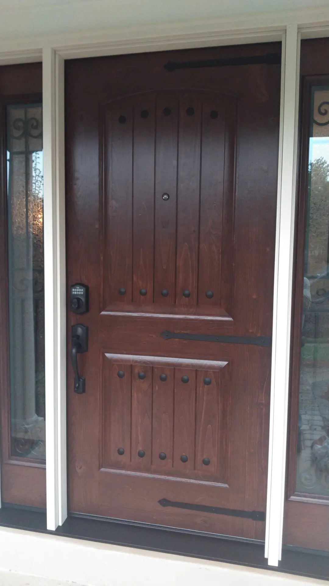 Stained wood entry door with a lever handle, sidelights and white trim.