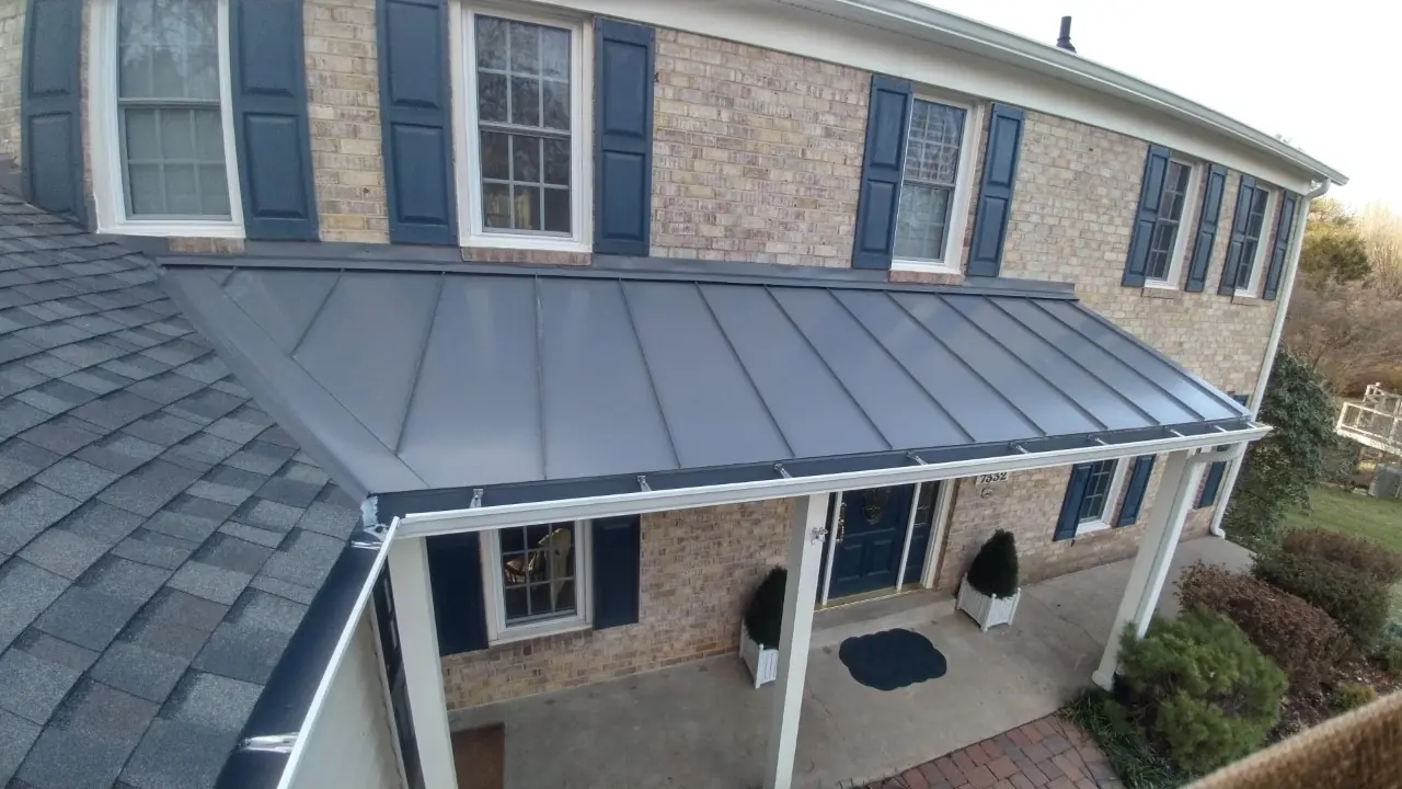 Gray metal porch roof and navy shutters on a brick colonial.