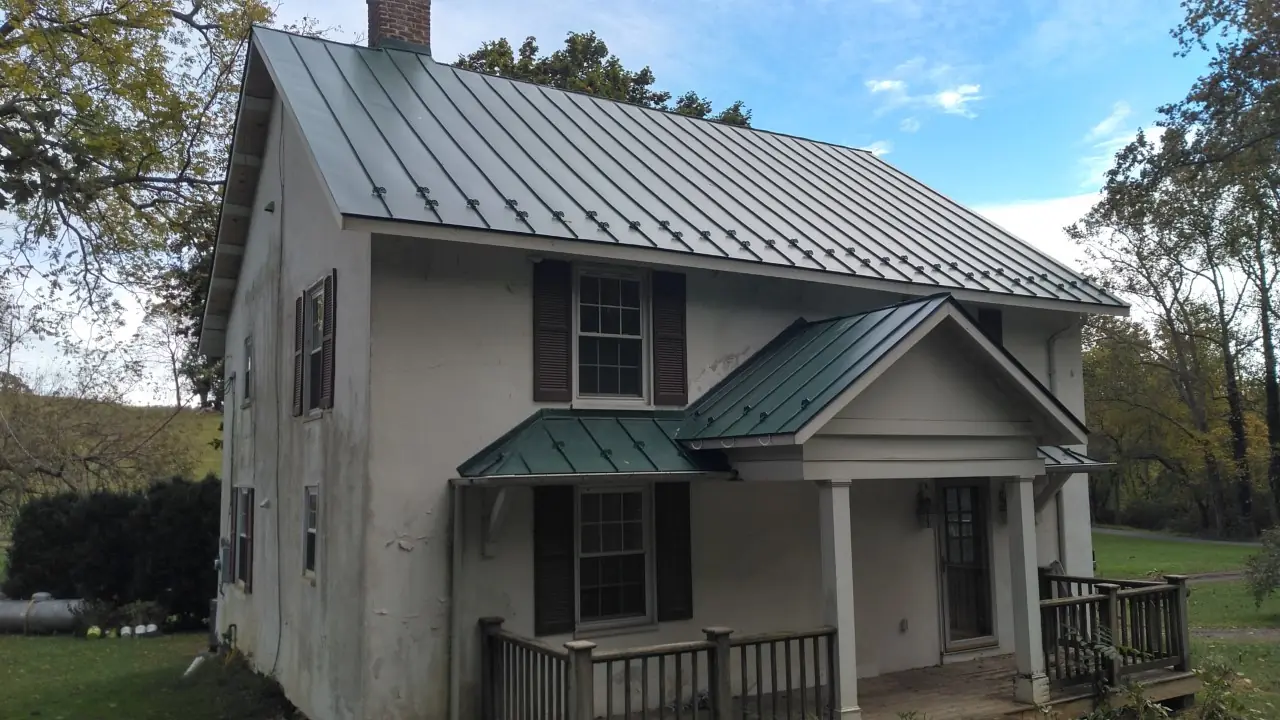 Side of the farmhouse showing a tall green metal roof and porch.