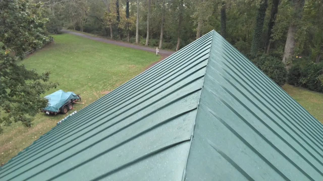 Green standing seam hip ridge with a lawn below.