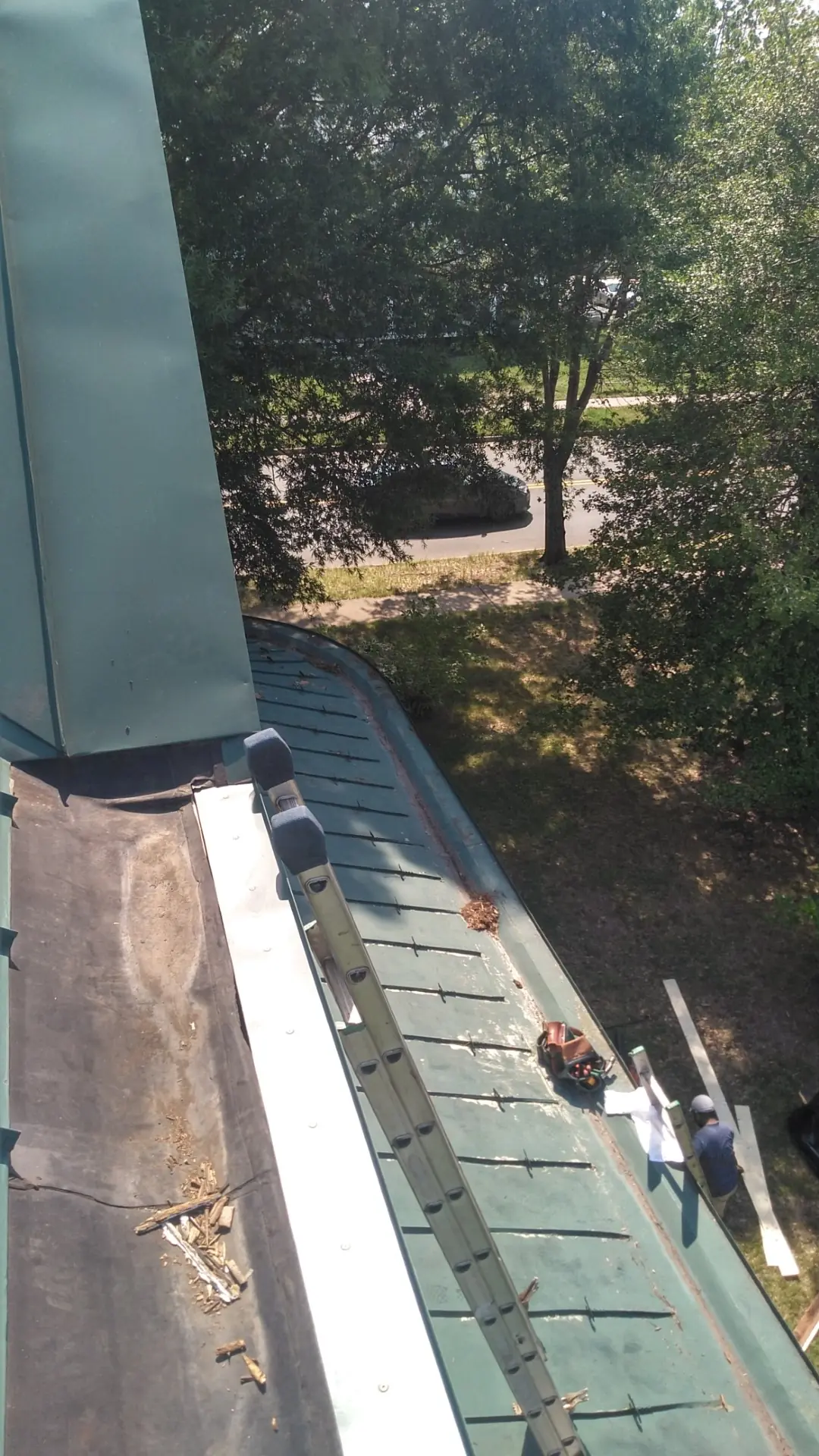 View down a lined box gutter with green metal panels to one side.