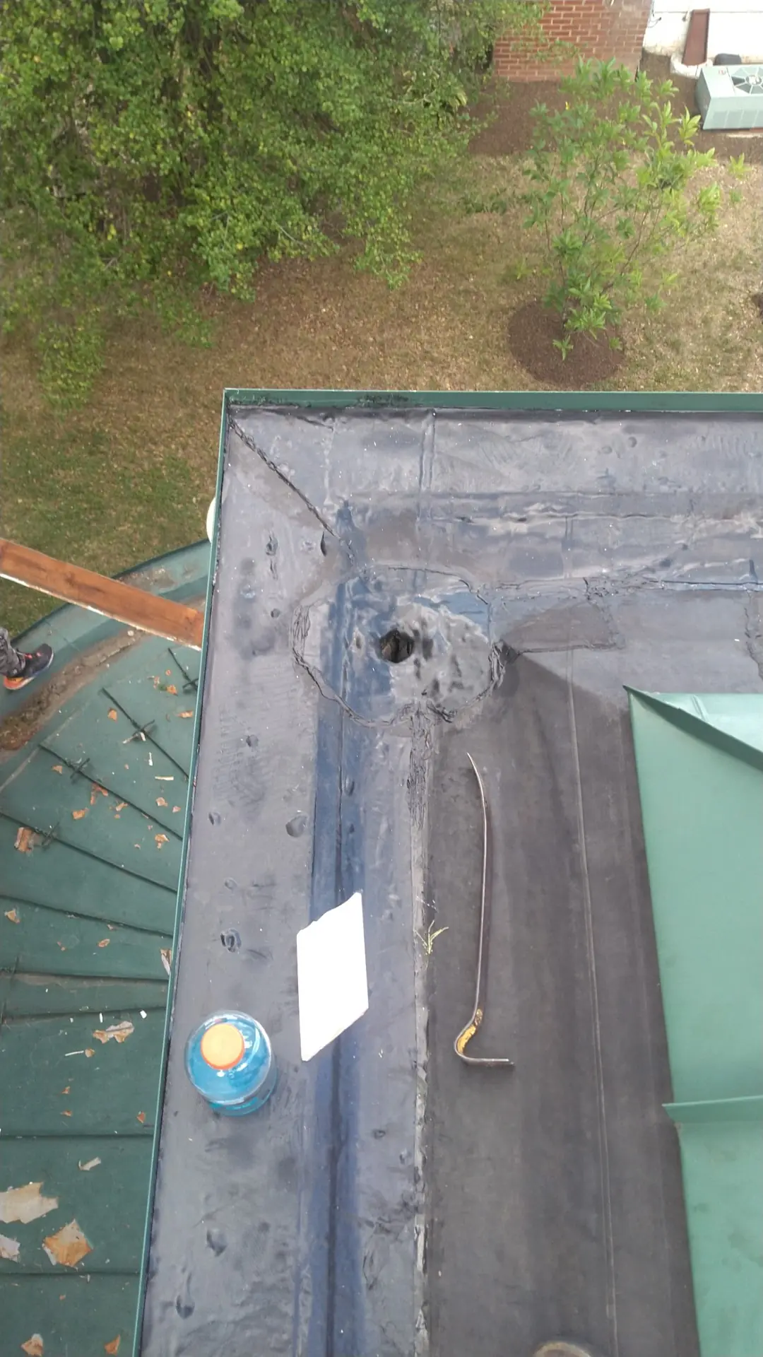 Corner of a lined gutter beside a green metal roof.