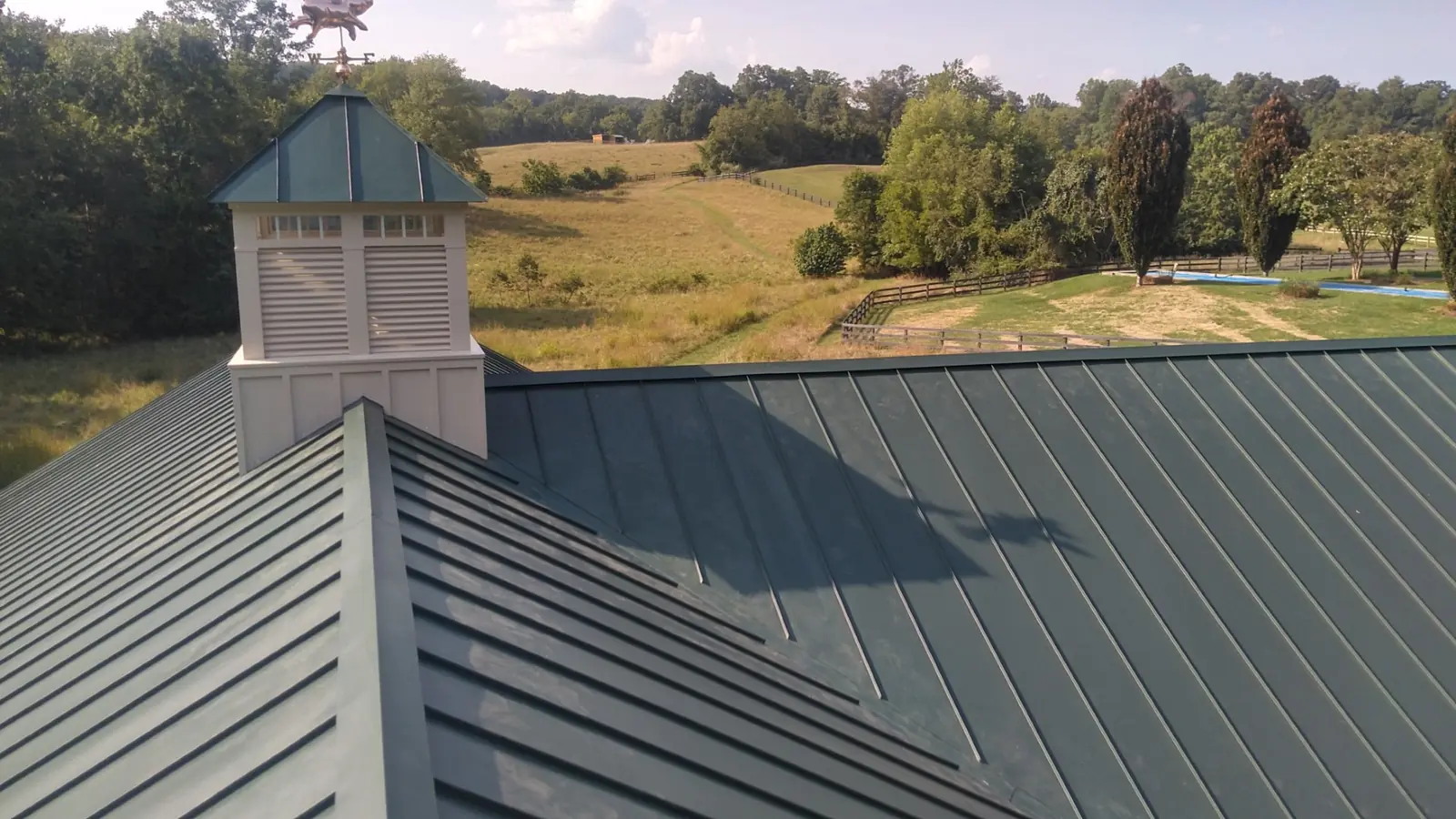 Cupola on a green standing seam roof with open farmland behind.