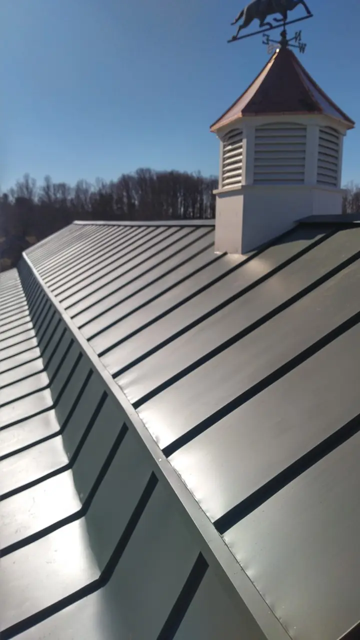 Cupola on a green standing seam roof with close panel seams.
