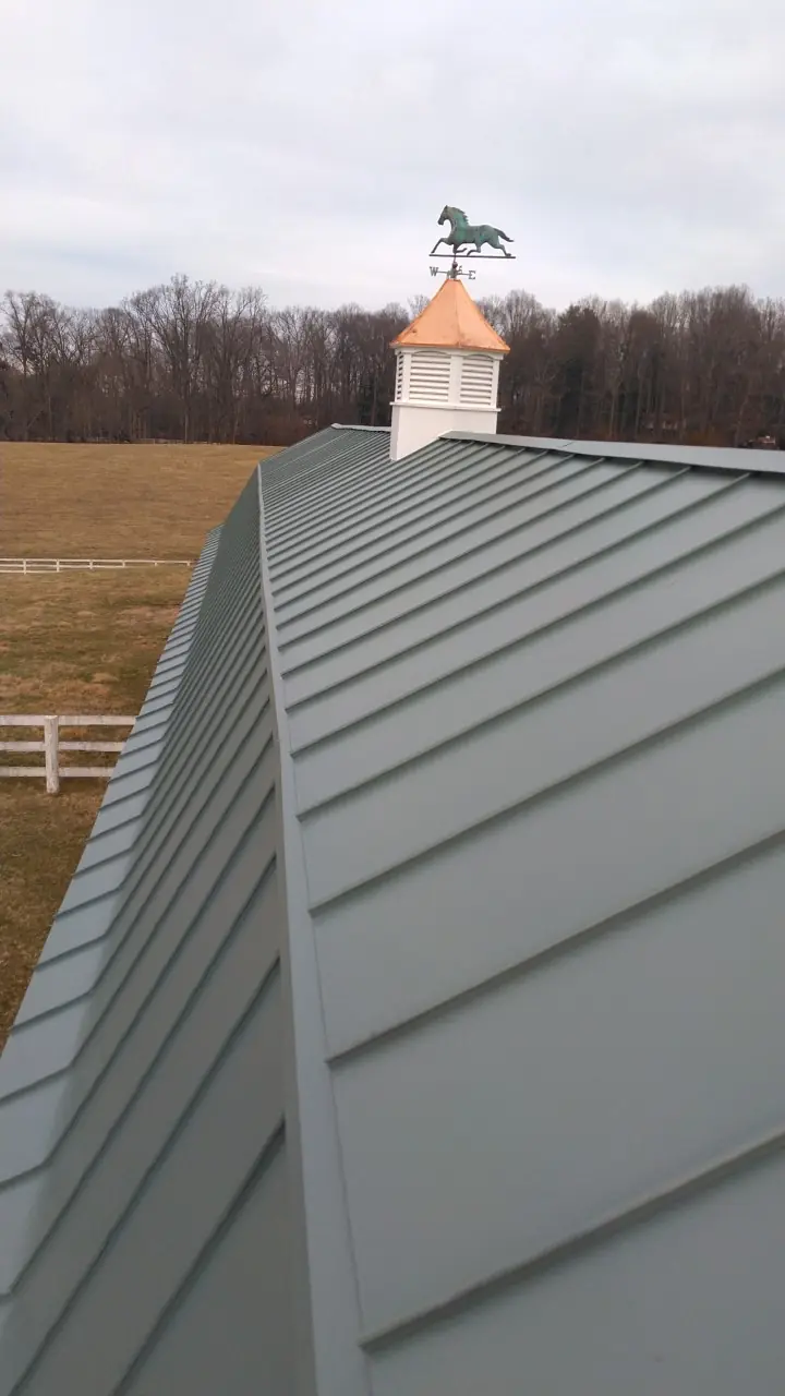 Green standing seam roof with a cupola and weather vane at the ridge.