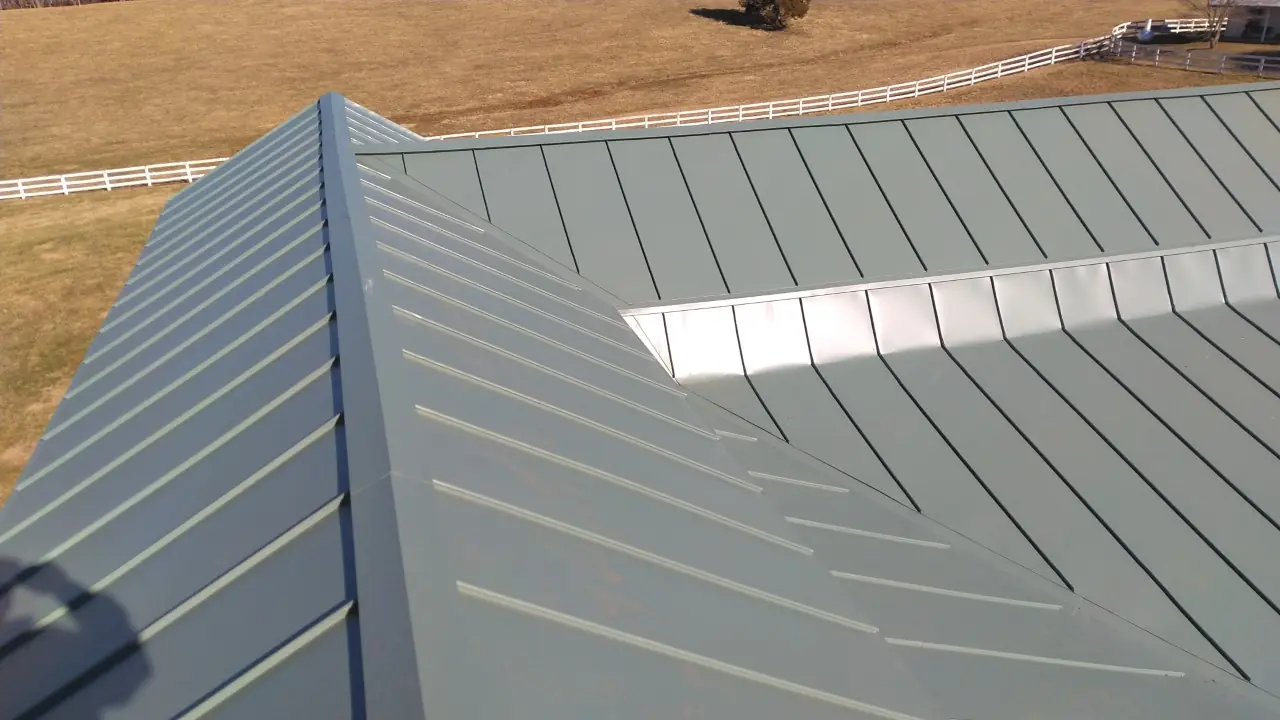 Green metal roof hip with a skylight strip.