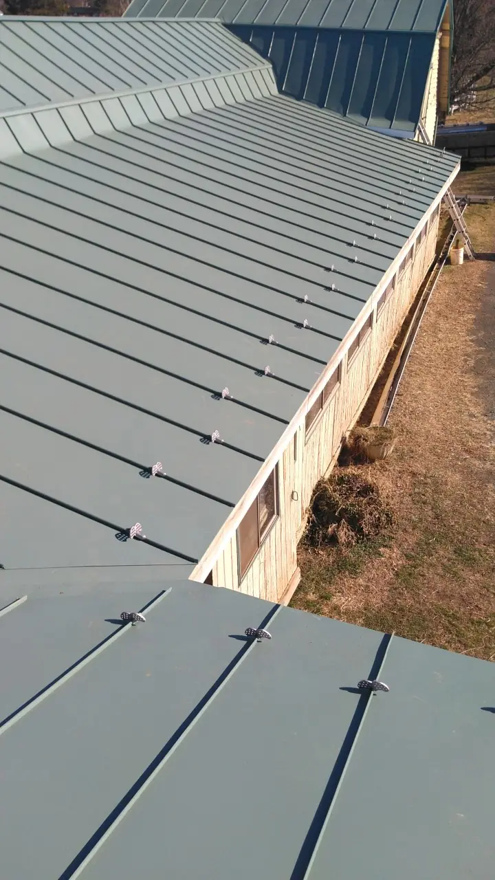 Edge of a long green metal roof running beside a building.