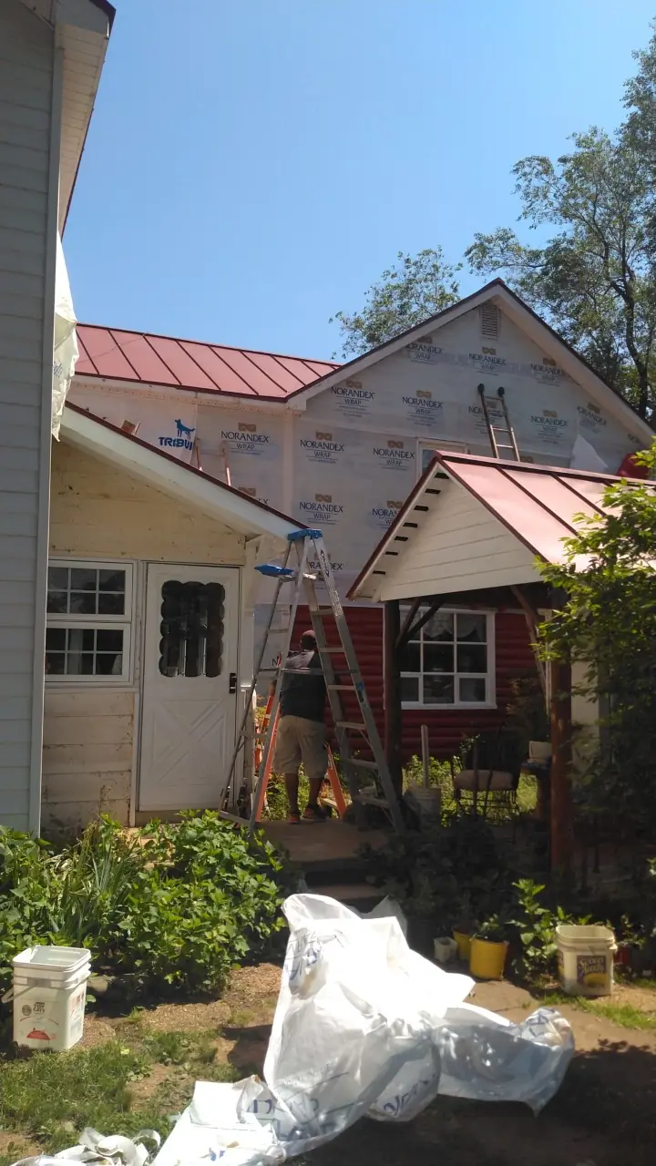 Side view of the house with red roofs, a white outbuilding and a gable under wrap.