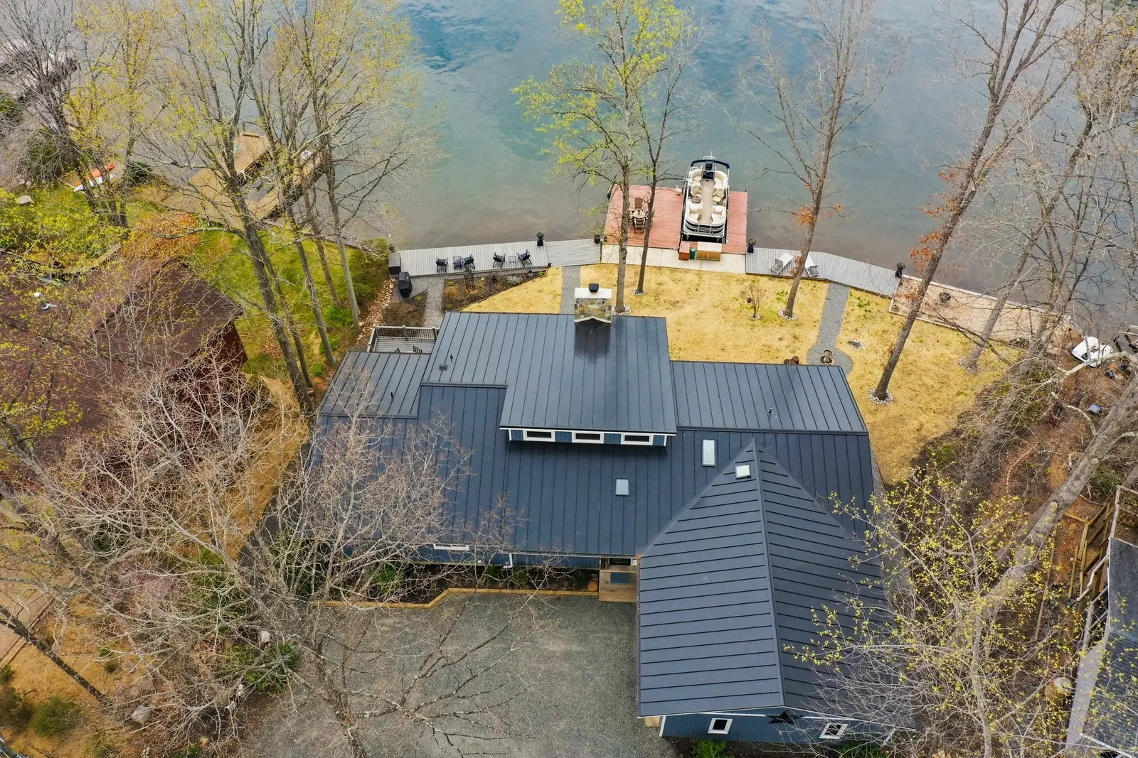Aerial view of the home and its dark roof beside the lake.