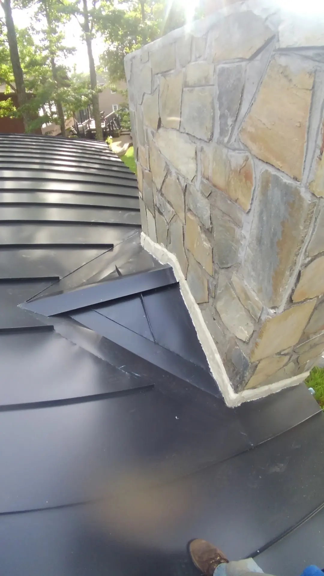 Dark metal roof with a stone chimney flashed into the panels.