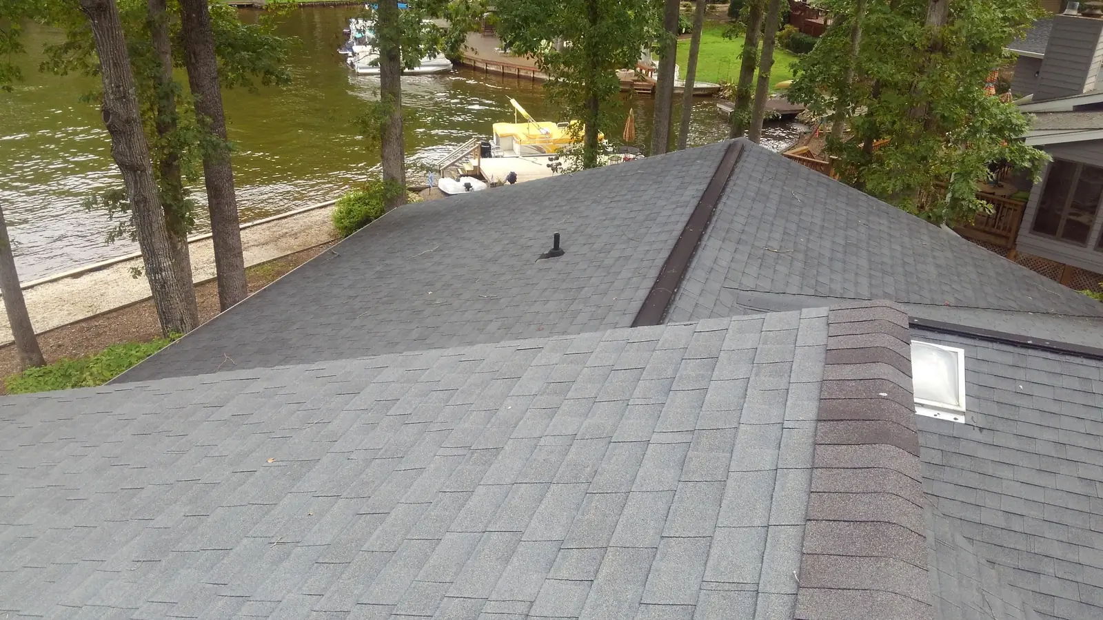 Before the work: gray shingle roof over the lake with a ridge and dormer.
