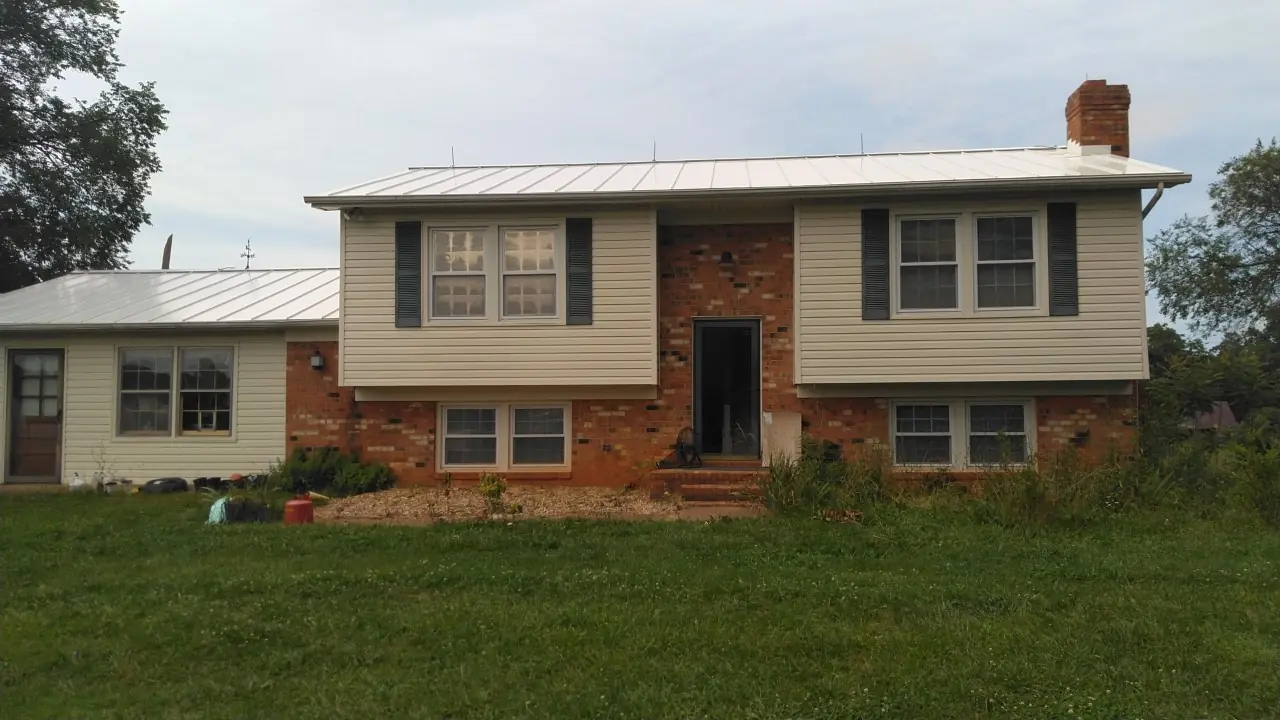 Brick and vinyl split-level home with a light silver standing seam roof.