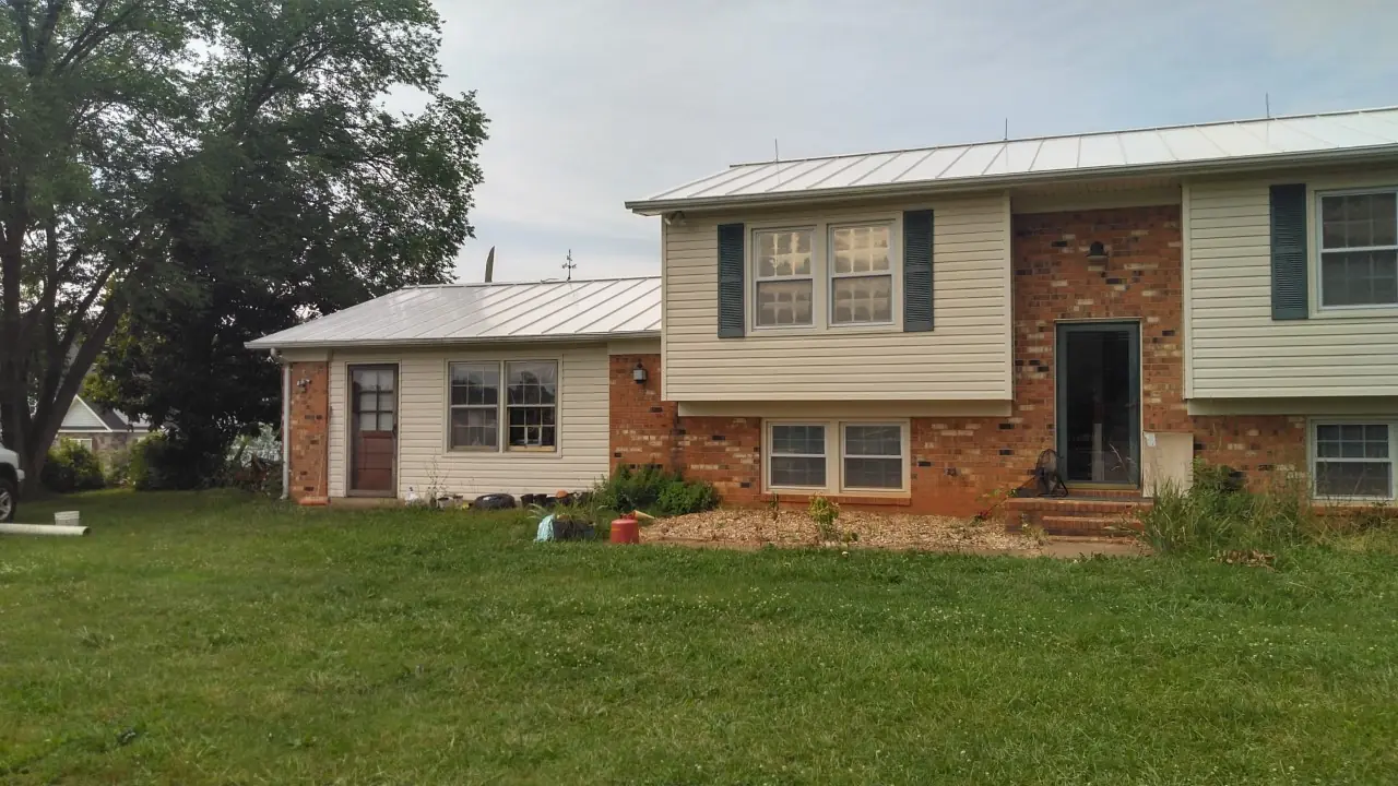 Light standing seam roofs over a split-level house and its attached wing.