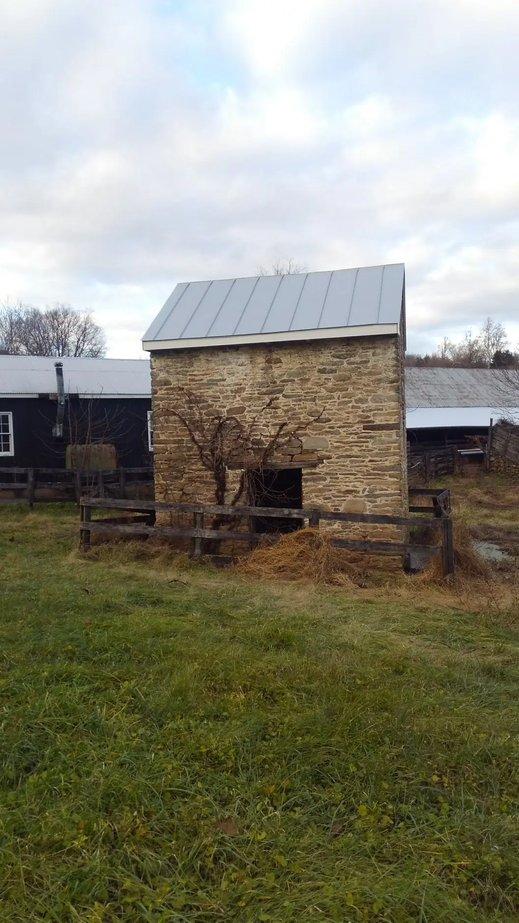 Small stone outbuilding with a light gray metal roof.
