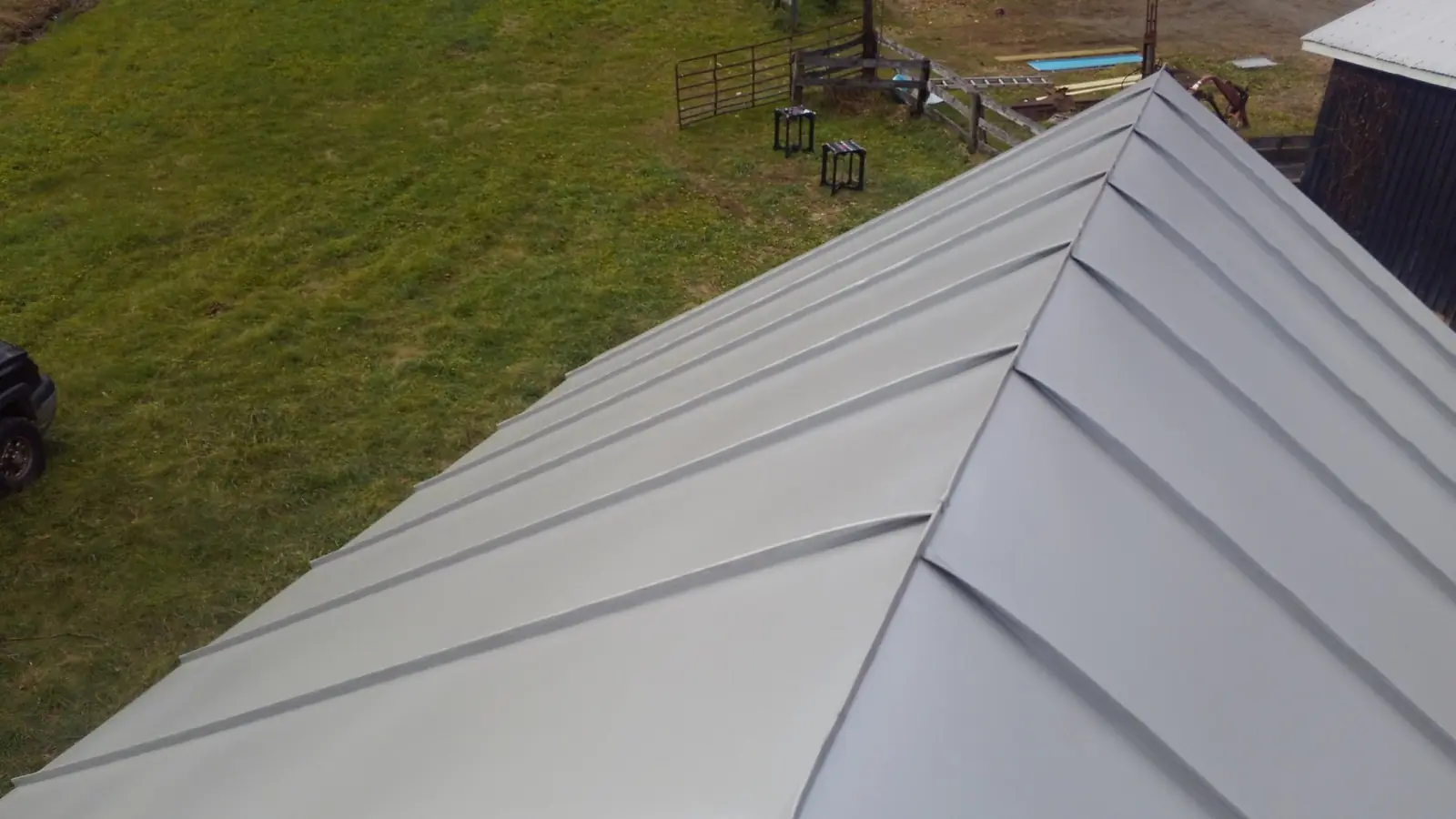 Light gray standing seam hip roof over open lawn.