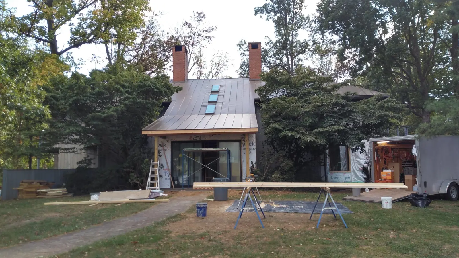 House front with a bronze standing seam roof, skylights and a ladder at the entry.