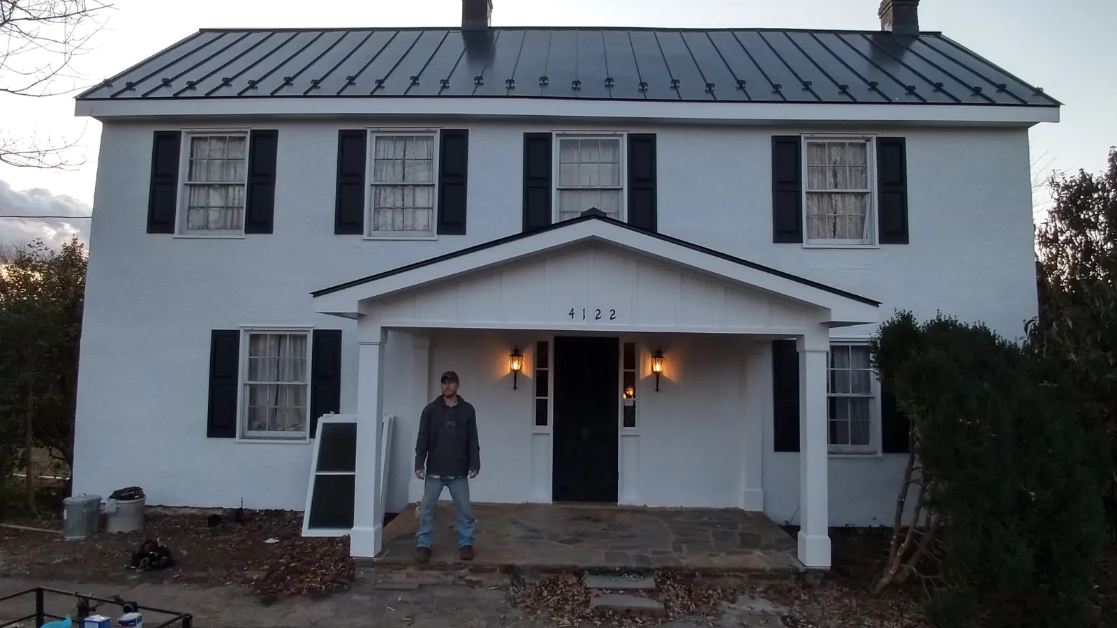 Two-story white colonial home with a dark standing seam metal roof and a front porch gable.