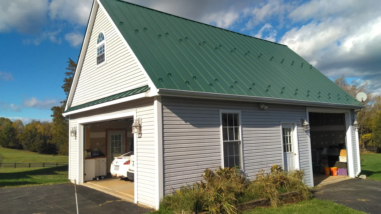 Detached garage with a steep green metal roof and vinyl siding.