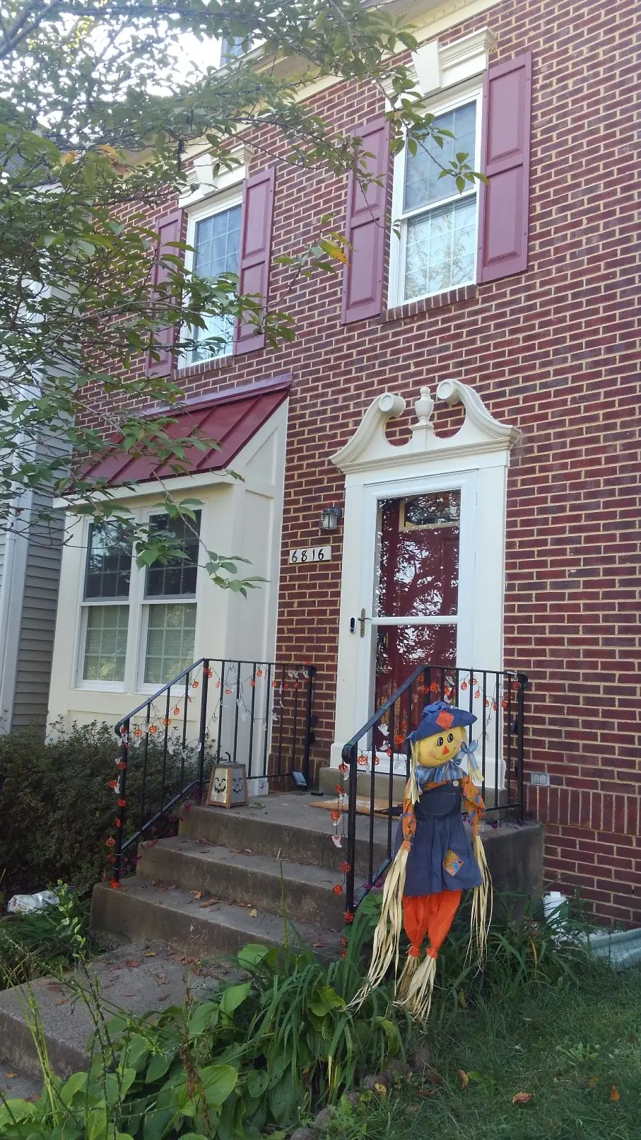 Brick townhome with a red metal bay roof and a red metal hood over the door.