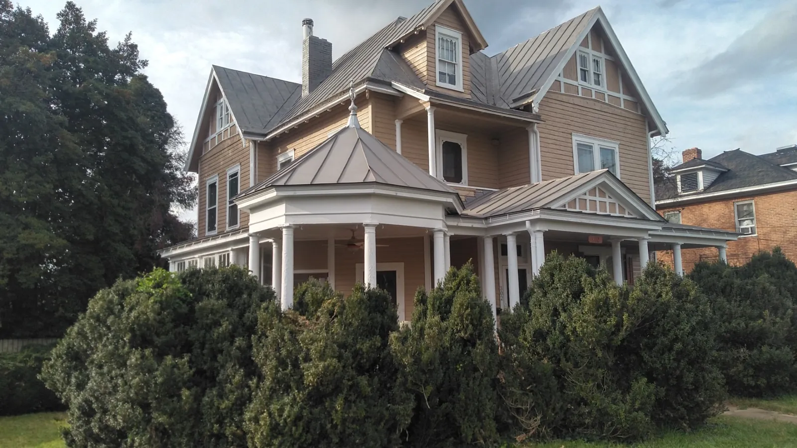 Victorian-style home with a standing seam metal porch roof and a wraparound gazebo corner.