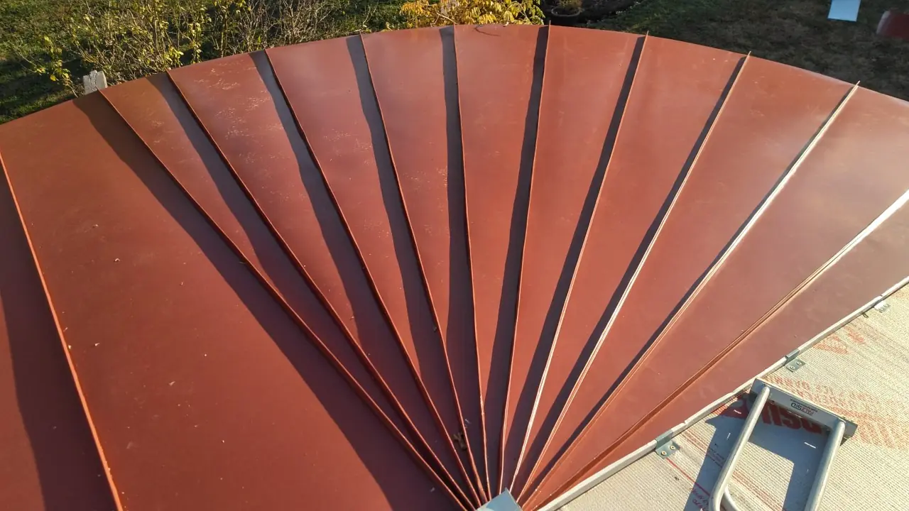 Red standing seam fan-shaped roof with tapered panels radiating from a point.