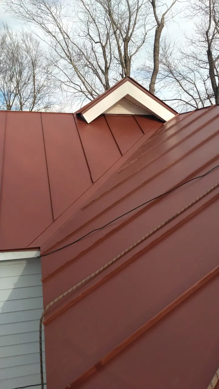 Red standing seam roof and ridge beside a small dormer.