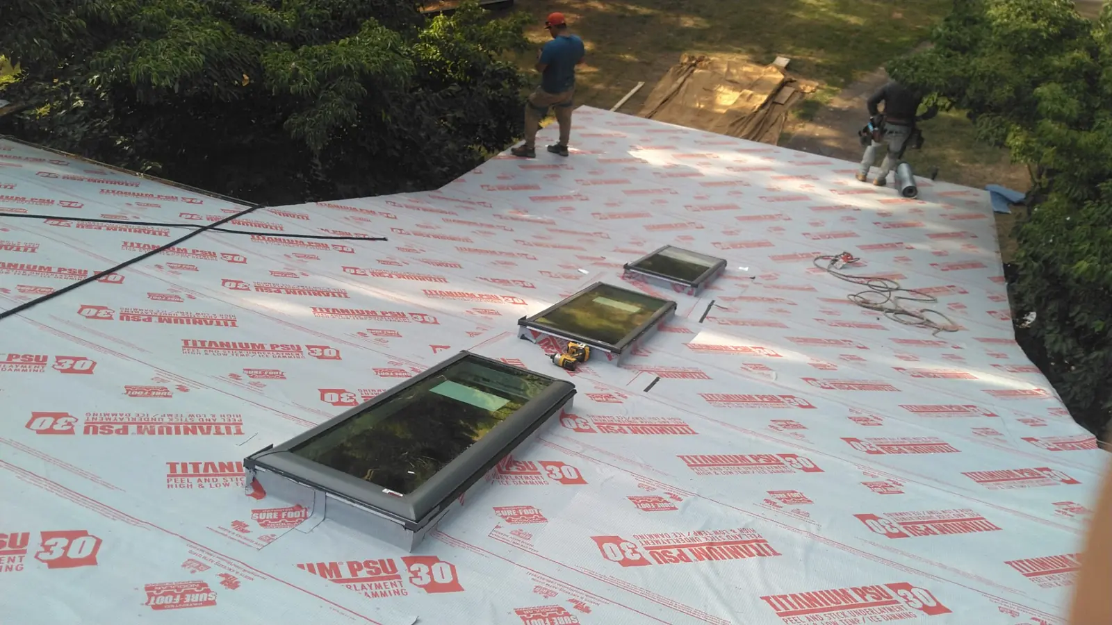 Crew members working on underlayment around skylight openings before the metal goes on.