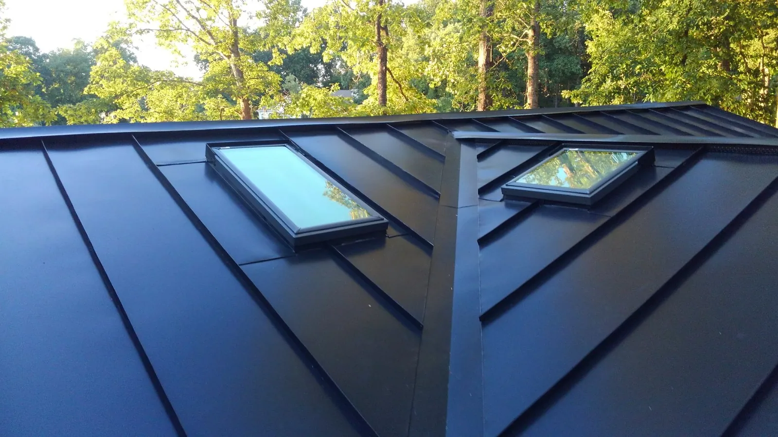 Close view of twin skylights integrated into a blue-black standing seam roof.