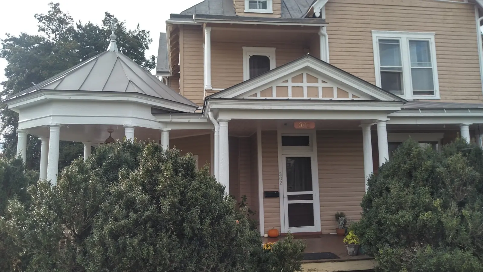 Corner gazebo and front porch with slate gray metal and white columns.