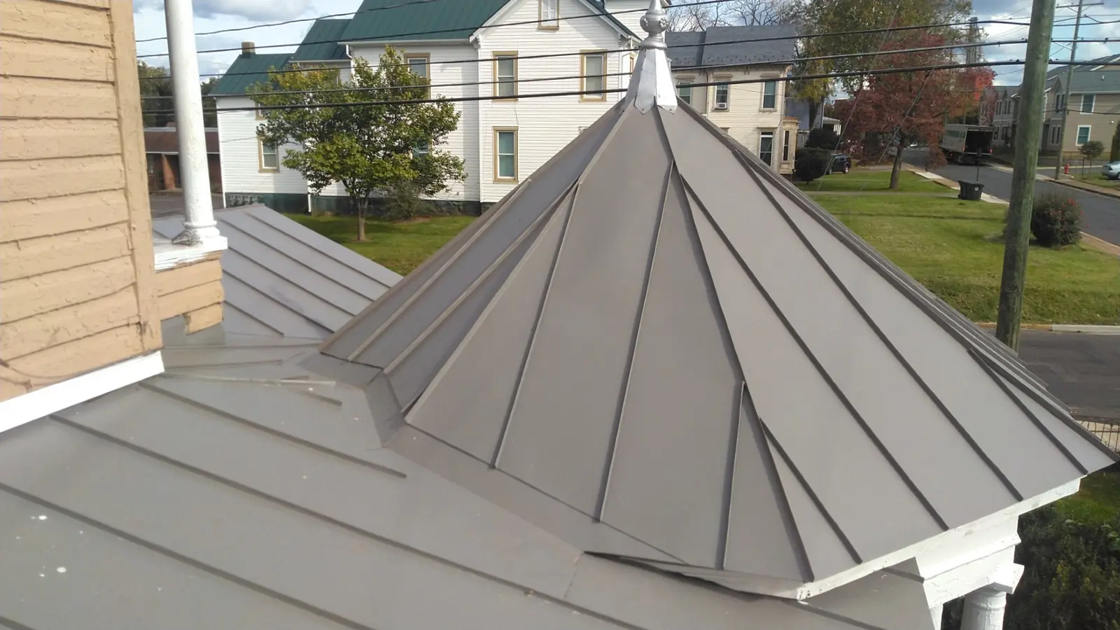 Slate gray standing seam pyramid roof over a corner gazebo.