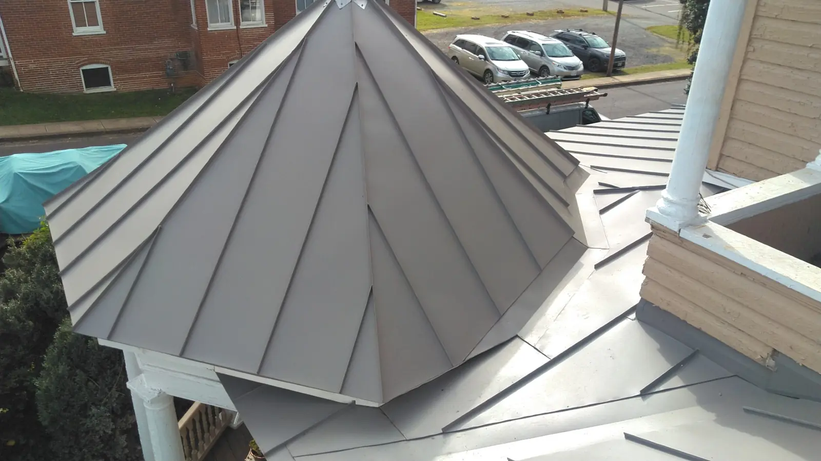 Slate gray metal gazebo roof with a white column and a rooftop view.