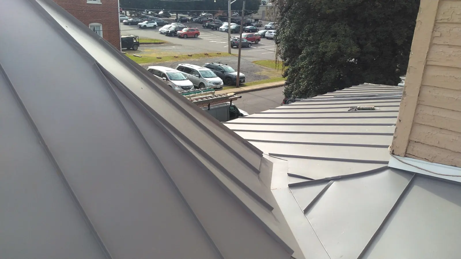 Slate gray standing seam roof plane and parking lot below.