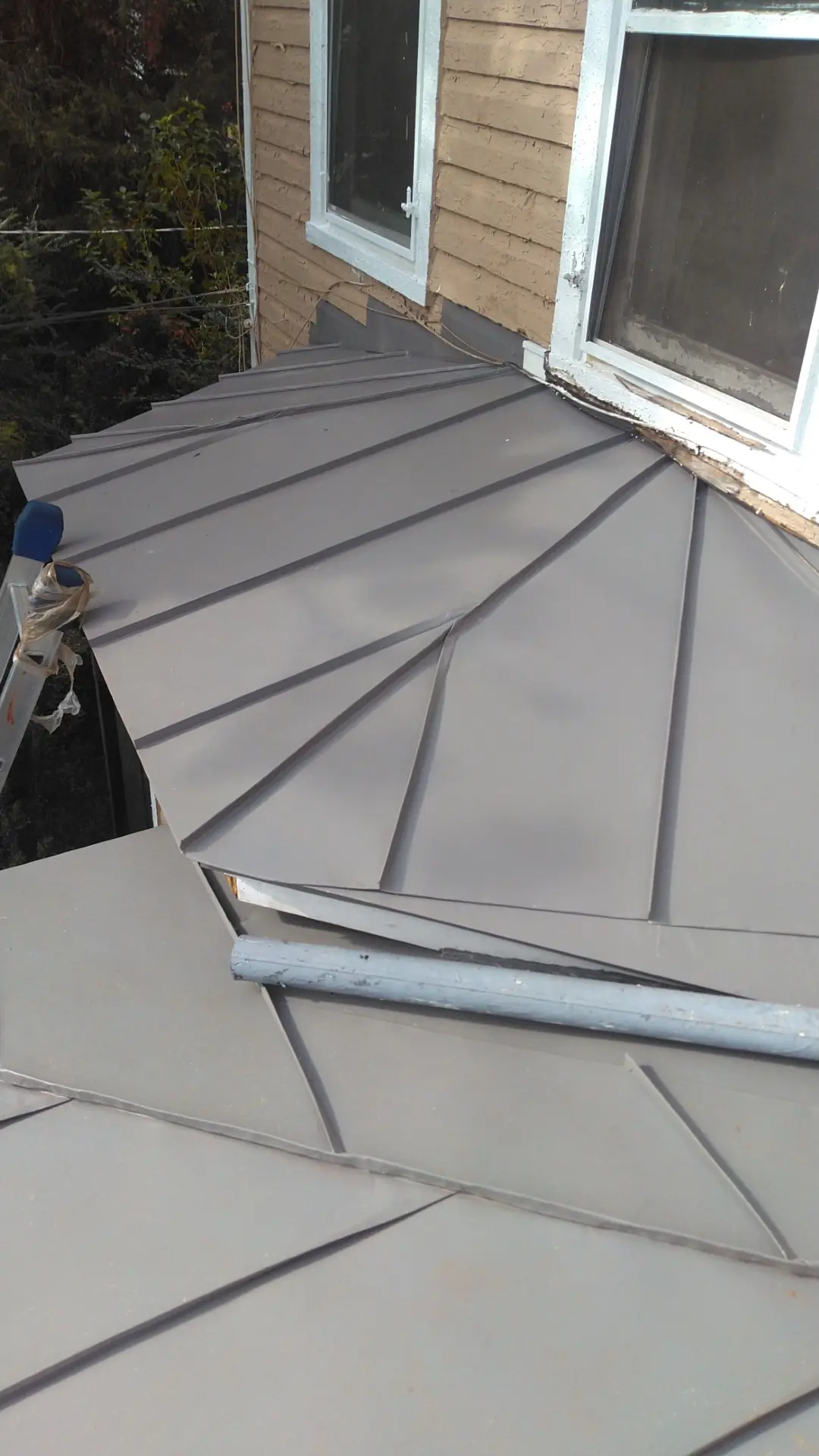 Slate gray standing seam hip and ridge with a drip edge.