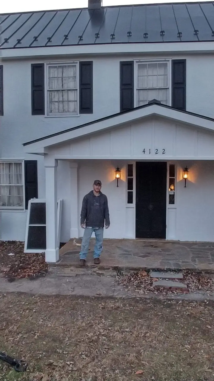 White colonial entry porch with a dark roof above; a person stands at the steps.