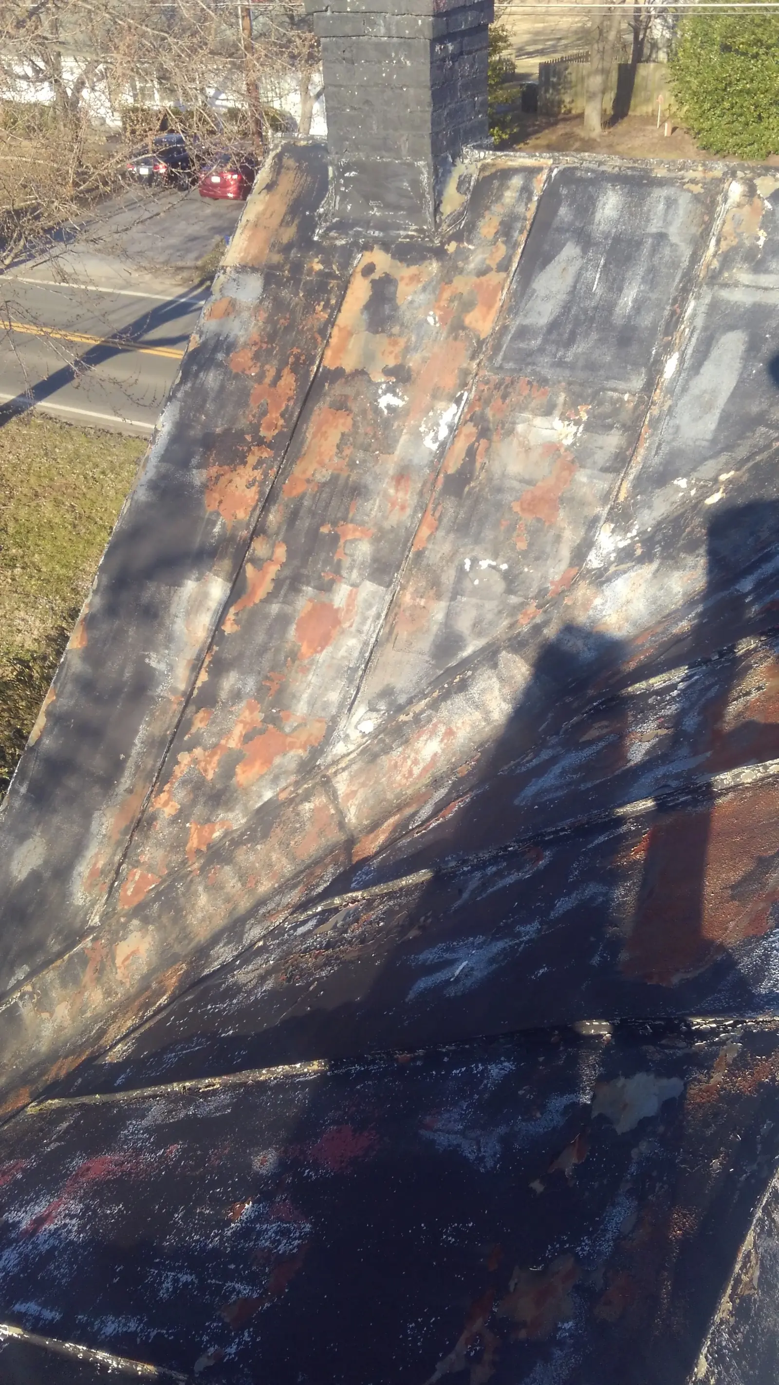 Closeup of an old brick chimney and the roof beside it.